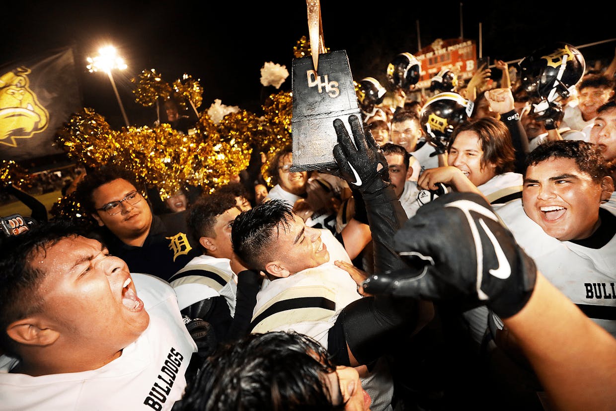 Senior Vicente Cardona hoists the fabled Pick trophy while being exhorted from teammates as the Douglas Bulldogs come away with the victory on the road against the Bisbee Pumas in Warren Ballpark Friday night.