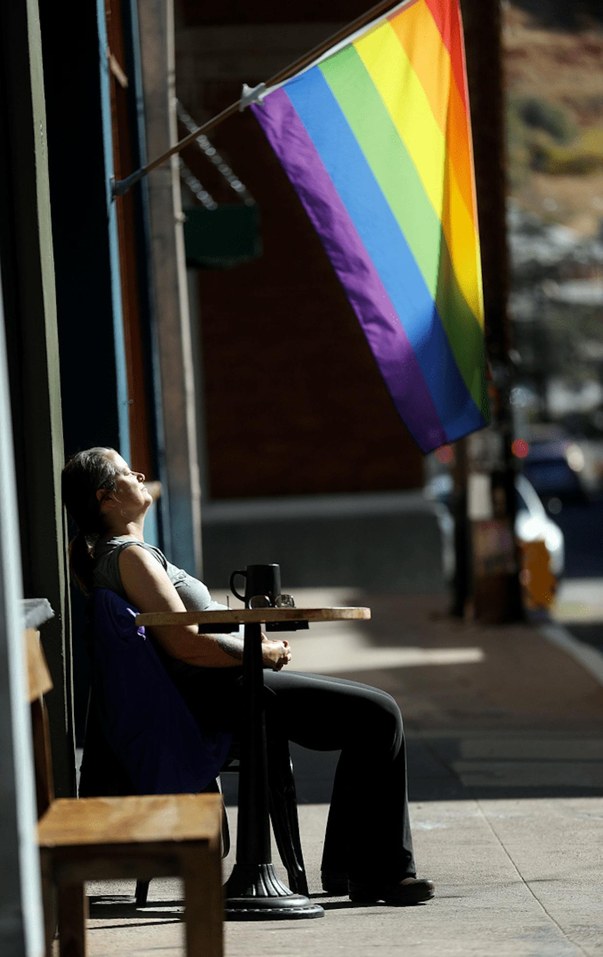 Bisbee resident Wendy Russell soaks in the heat during an otherwise cool Bisbee morning last week in front of KAFKA coffee shop.