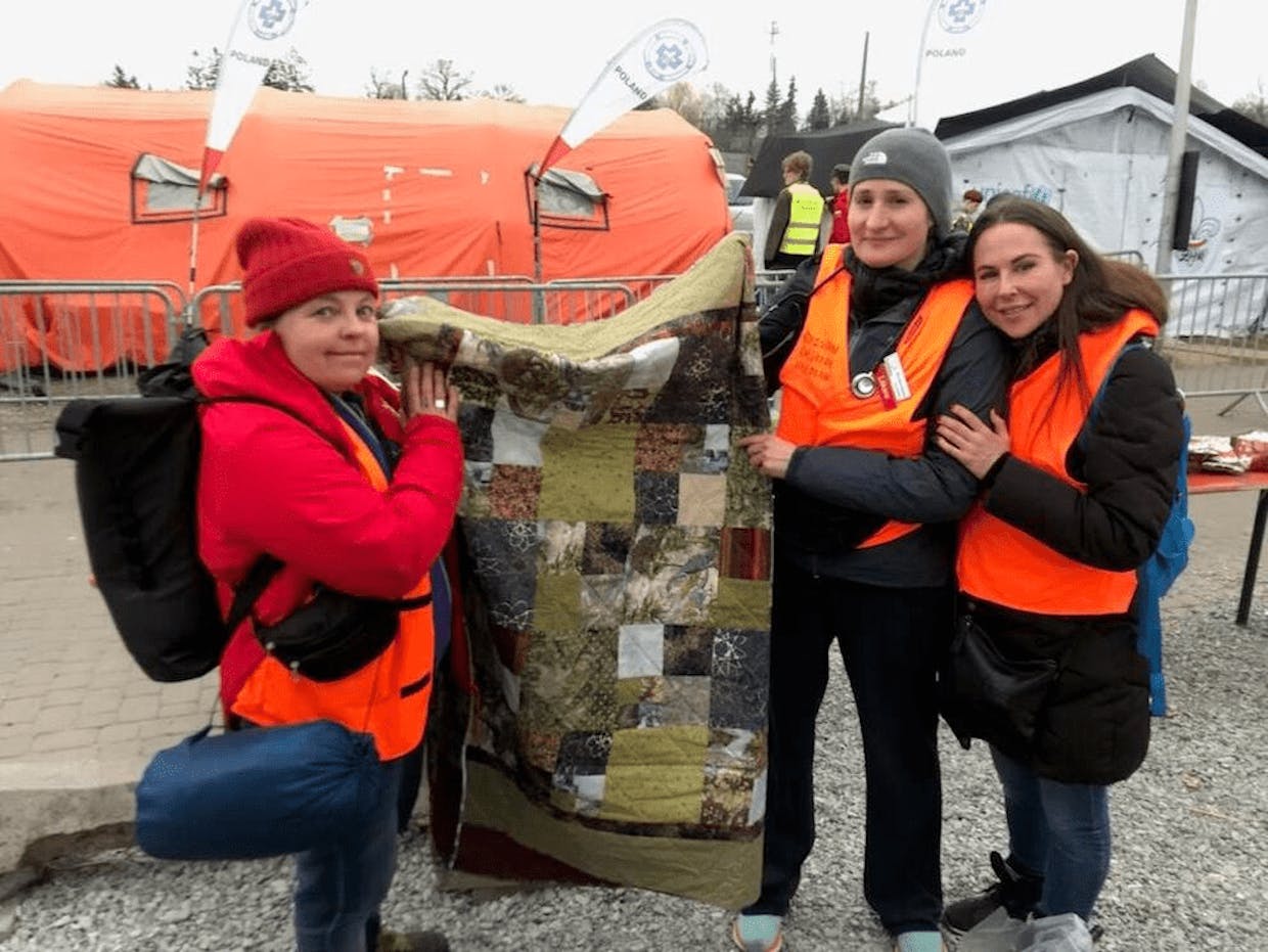 Nurses hold up a quilt donation that would ultimately be given to a man in  Ukraine who had been sitting in the rain and sleeping outside for weeks. (Mike Mitchell photo)